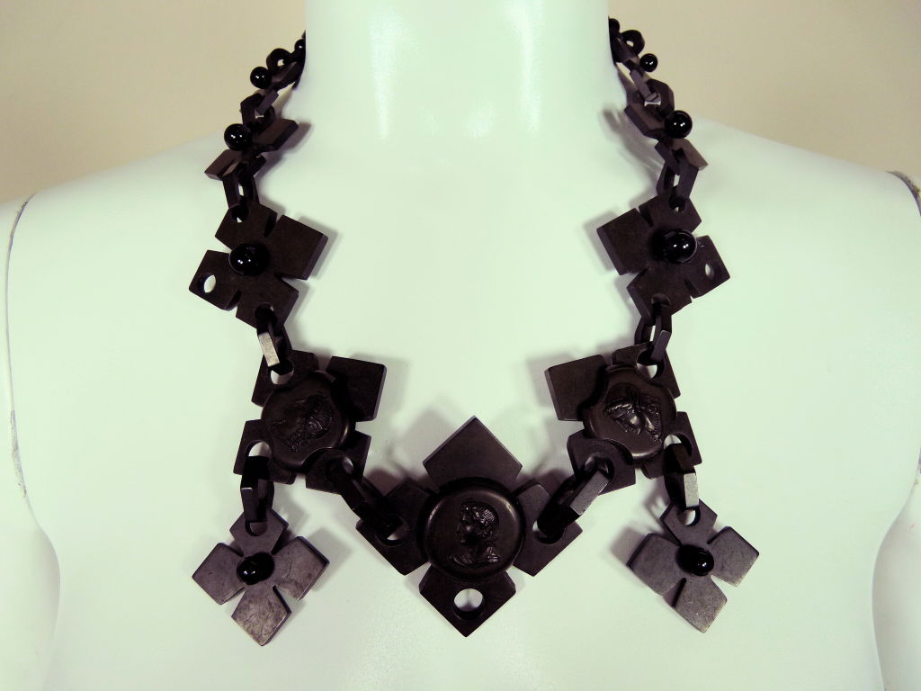 Gutta percha Victorian mourning necklace featuring carved black cross shaped medallions with cameo cabachon detail, jet black ball detail and  beveled link connectors. Silver hook closure.