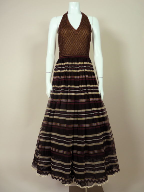 Beautifully detailed Christian Dior halter gown from the 1980's. Bodice is a rich chocolate brown with passementerie knotting and is attached to the chiffon skirt, which is an alternating-color stripe.  The skirt sits on top of a layer of organza. 