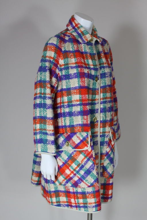 Vibrantly colorful plaid wool coat from Bonnie Cashin has raglan sleeves, oversized front patch pockets with flap closure and signature Cashin brass turn closures. All edges are finished with white leather piping.