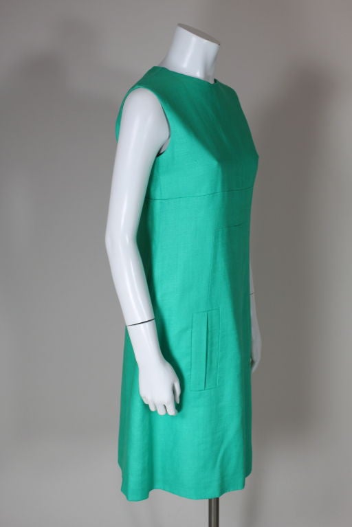 Sleeveless teal linen shift dress from Donald Brooks with mod, geometric seaming has two oversized welt pockets in front and a skirt that slightly a-lines. Matching plastic buttons fasten the back. Fully lined.<br />
<br />
Measurements:<br