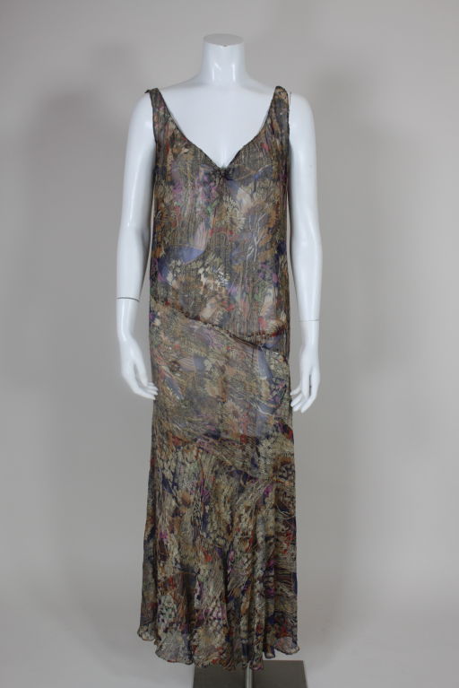 Gorgeous deco 1920's sleeveless blue silk lamé gown printed with a painterly floral in shades of lilac, yellow ochre, coral, apple green and tan. Gown is seamed asymmetrically and skirt portion is cut on the bias for added flare.<br />
<br