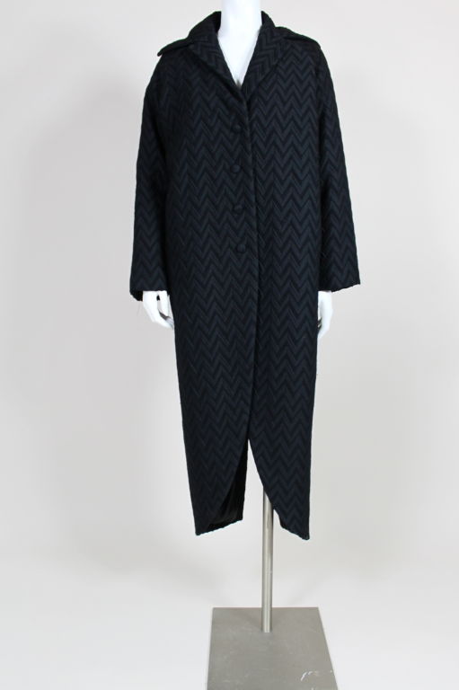 Textured wool zig zag motif coat from Romeo Gigli has swallowtail hem, notched shawl collar, raglan sleeves and button front. Fully lined with with two hidden pockets inside coat front. <br />
<br />
Measurements--<br />
<br />
Bust: 48