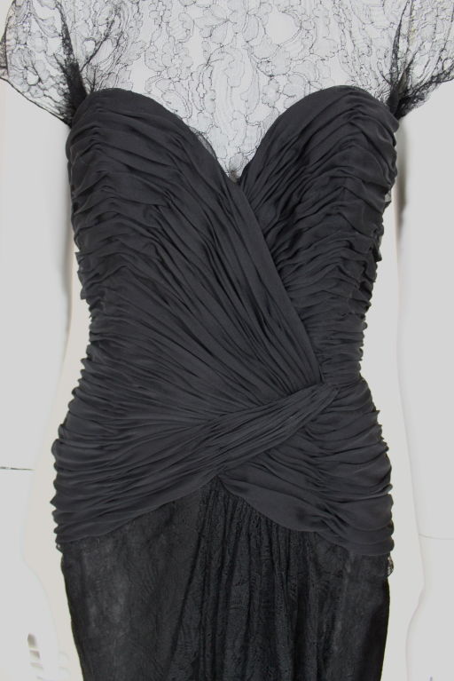 Gorgeous black silk chiffon and lace cocktail dress from Oscar de le Renta. Bodice is crafted from hand-tacked pleated chiffon that is sculpted into a sweetheart neckline and follows the contours of the body over the hips. Black scalloped chantilly