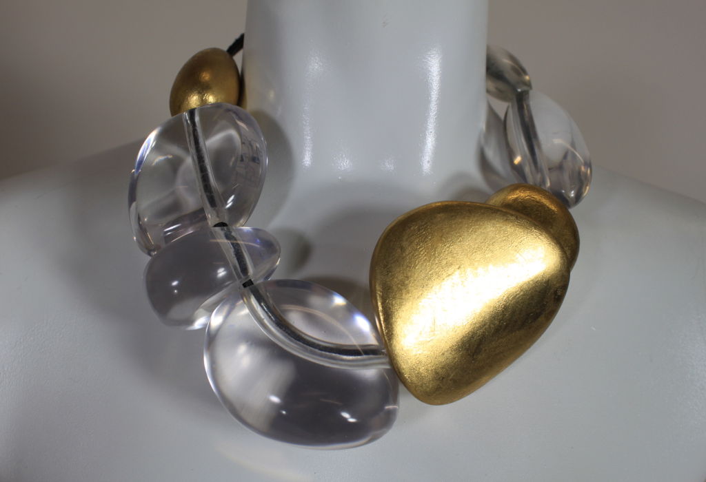 Gorgeous oversized statement necklace from designer Gerta Lynggaard features irregular shaped and sized lucite baubles alternating with gold lacquered wood beads on a leather cord. Necklace is fastened with a toggle style closure.<br />
<br