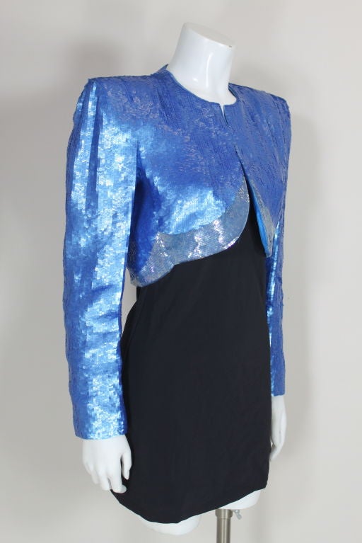 Gorgeous cropped evening jacket from Carolina Herrera is fully embroidered with opaque cerulean blue sequins that are accented by a band of iridescent sequins at hem. Jacket has architectural, padded shoulders. Fully lined in blue china silk. <br