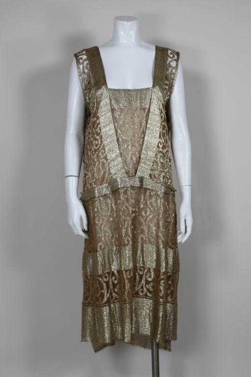 1920s gorgeous gold lamé lace party dress has classic Art-Deco drop-waist silhouette. Lace is crafted from metallic threads woven across metallic net in panels of scrolling designs that alternate with solid bands of gold lamé. Lined in gold silk