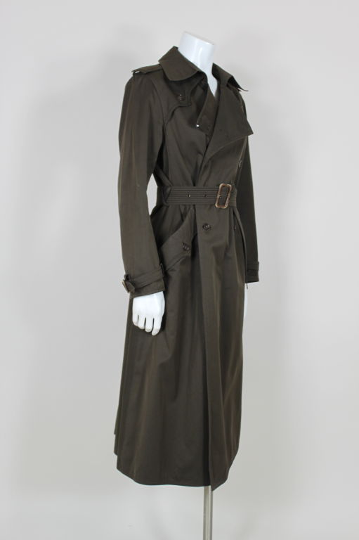 Iconic, belted chocolate brown cotton twill trench coat from Yves Saint Laurent Rive Gauche with matching patent leather buckles and tortoise buttons. Double breasted coat has stylized yokes and epaulets at shoulders. <br />
<br