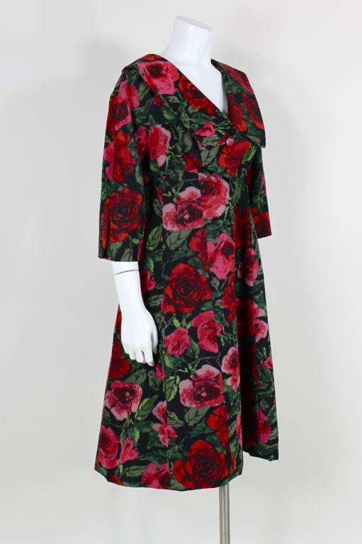 Richly colored bengaline cocktail dress from James Galanos features a moire rose pattern in shades of scarlet, pink and green that is woven into the fabric. Empire waist dress has an oversized collar and bodice that wraps and fastens with front