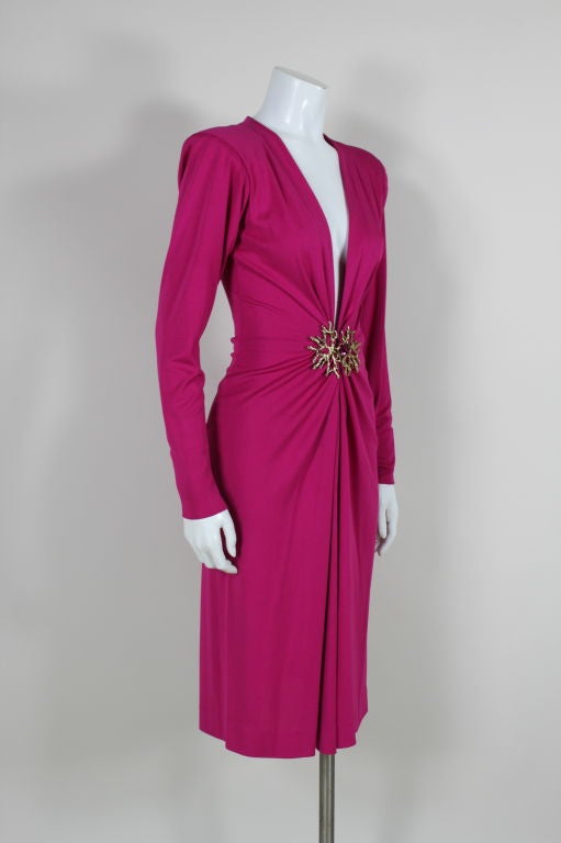Ultra sexy, super-slinky vibrant fuschia jersey cocktail dress from Yves Saint Laurent features a plunging V-neck accented by a gold tone coral branch clasp decked with fuschia rhinestones. Ruching radiates from coral hardware. Shoulders are lightly