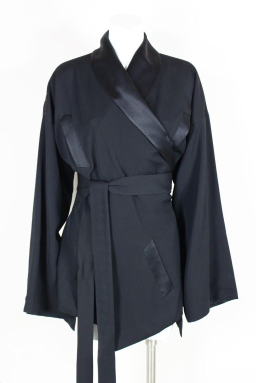 Amazing kimono inspired tuxedo jacket from Jean Paul Gaultier is done in a fine wool twill trimmed with silky black satin. Like a kimono, the jacket is open at side seams and ties with an attached twill and satin sash belt. Bespoke inspired