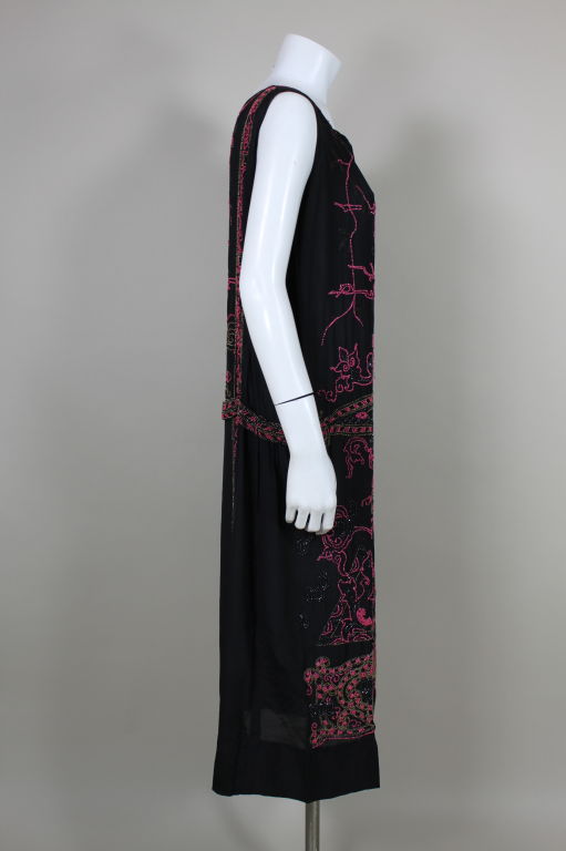 Exquisitely beaded 1920's art deco silk crepe party dress features a hot pink Japanese cherry blossom inspired motif flanked by geometric shapes, scrolling panels and deco flowers. Pink beads are accented with black glass and multi-color wood seed