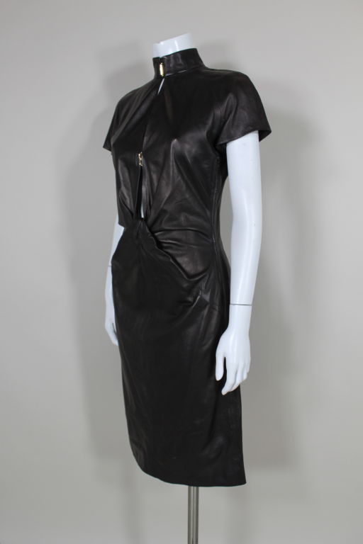 Ultra chic dress from Yves Saint Laurent is made from the softest Italian leather with a low cut neck, raglan sleeves, a high stand up collar and radiating pleating at the waist. Collar and plunging neck are fastened with YSL logo embossed goldtone