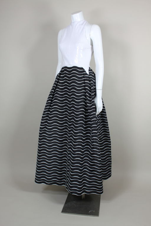 Classic, sexy and ultra chic iconic ballgown from Geoffrey Beene features a halter neck bodice with a criss-cross back embroidered all over with chalk white micro sequins. Bodice is sewn to the skirt in such a way that the midriff peekaboos through