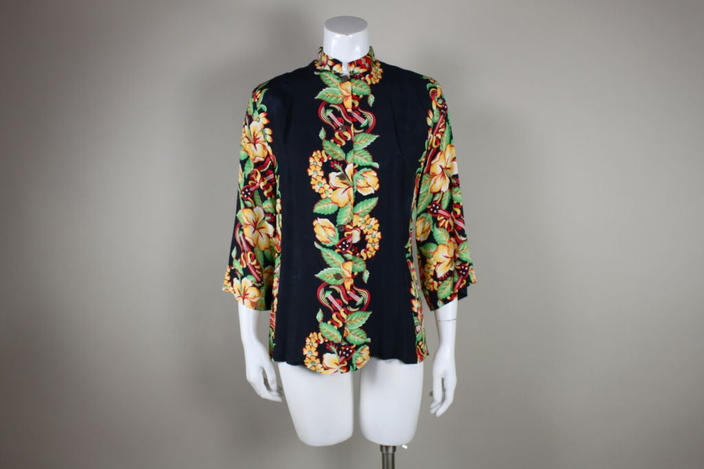 A gorgeous example of collectible 1940's Hawaiian rayons, this blouse features a colorful hibiscus and ukelele border print on a navy ground. The silky, lightweight rayon lends itself to the swingy trapeze silhouette, with a single inverted pleat in