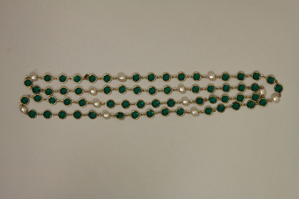 Iconic, extra long necklace from Chanel features bezel set faceted emerald green glass gems accented with costume freshwater pearls. Cartouche is inscribed with date of creation: 1981. <br />
<br />
Measurements-<br />
Length: 56”<br />
Green