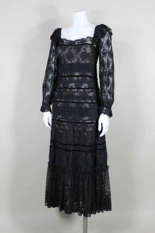 1970s tiered lace gown from Giorgio di Sant'Angelo is decorated with bands of thin velvet and satin ribbons, contrasting floral lace and cross stitch trims. Gown is lined with metallic black and red floral lace that peeks through. Sheer lace long
