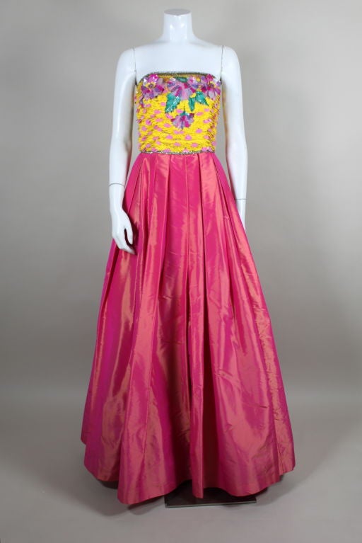 Vibrant, gorgeous ball gown from Escada has a full, voluminous skirt done in a hot pink iridescent taffeta pleated from the waist. Strapless bodice is embellished with spangles of vivid yellow and iridescent pink paillettes and decked with