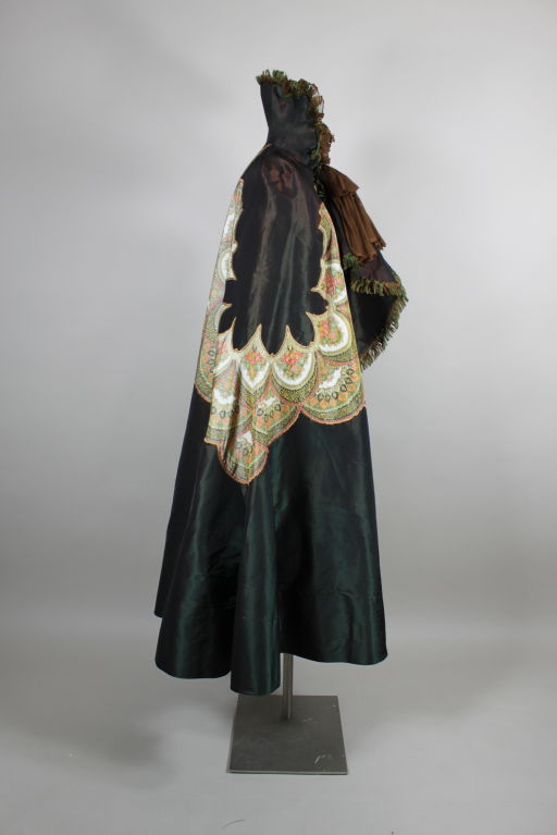 Dramatic and beautiful iridescent forest green silk taffeta Victorian cape features an inserted scalloped chiné floral panel that is hand sewn into the fabric with a scalloped border of golden silk thread. Stand up collar is trimmed in green and