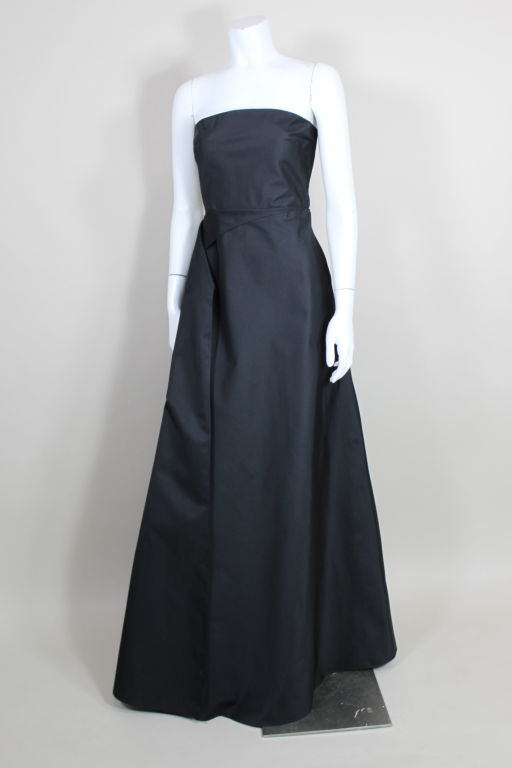 Sculptural, sultry strapless taffeta gown from Calvin Klein an architectural swag that sweeps from front to back. A completely exposed back is highlighted by three thin bands of elastic. Skirt is slit up the back to offer a glimpse of some skin.