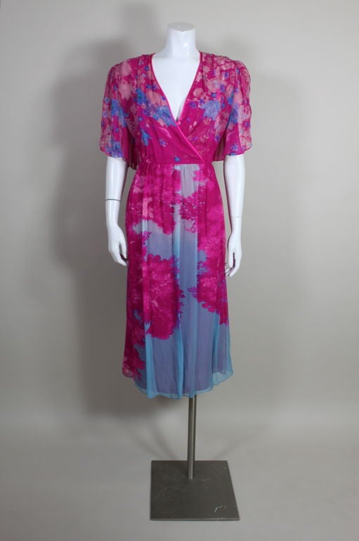 Circa 1980's Hanae Mori silk party dress features a bold, photographic floral placement print. The wrap style bodice is printed with electric blue, lavender and white flowers, and is edged in hot pink satin trim. Sheer peekaboo flutter sleeves are
