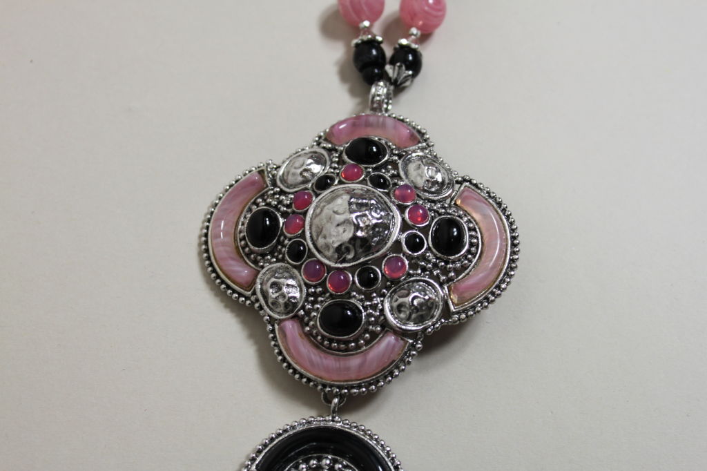 Circa 1971 necklace from Christian Dior is made from marbled pink glass rounds and ridged opaque black beads and features a bold rounded cross pendant decked with geometric glass cabachons and silver granulation.<br />
<br />
Measurements-<br