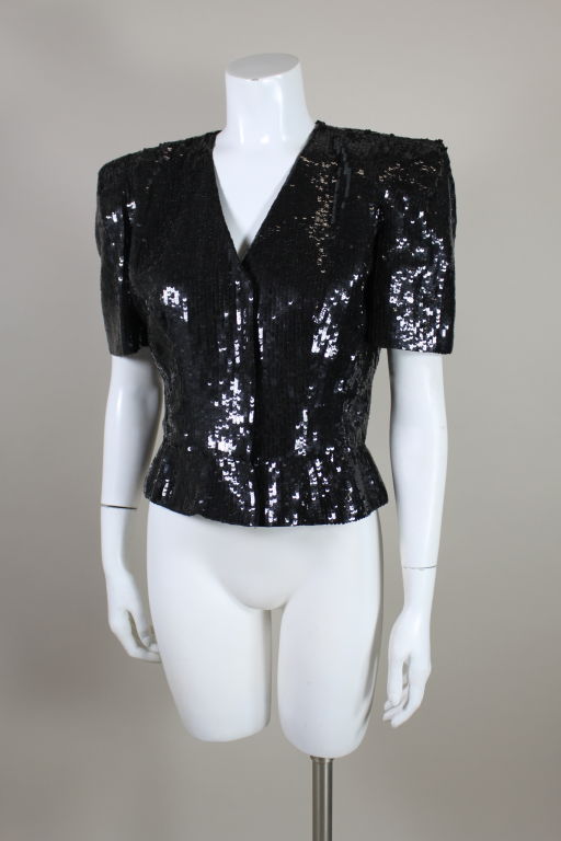 Carolina Herrera dramatic black sequined short sleeved evening jacket with floral embroidered application on back.  Jacket is tailored to fit at the waist.  A great piece to wear over formal evening wear or perfect with jeans.<br />
<br />
Bust: