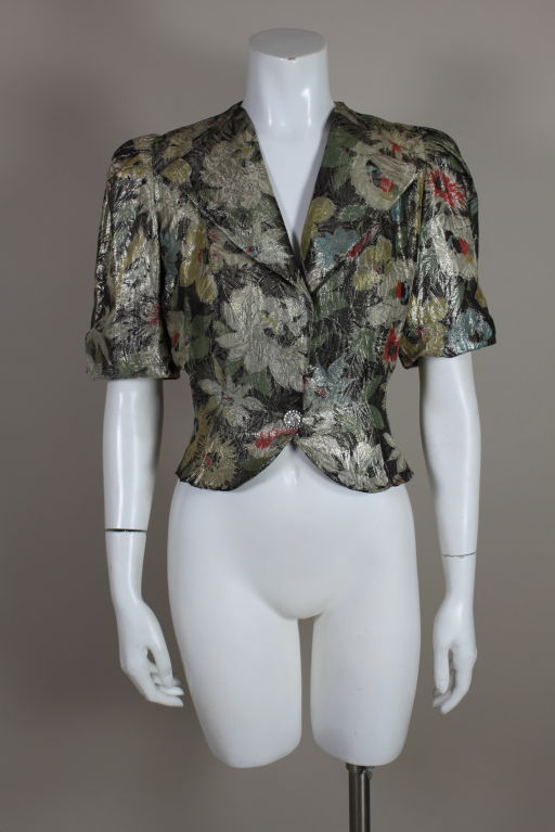 Gorgeous 1930’s jacket is made from the most beautiful lamé with painterly flowers in shades of pale yellow, coral, sky blue and mint green shot with silver metallic threads. Shoulders are softly sculpted with pleats, sleeves are done in a trumpet
