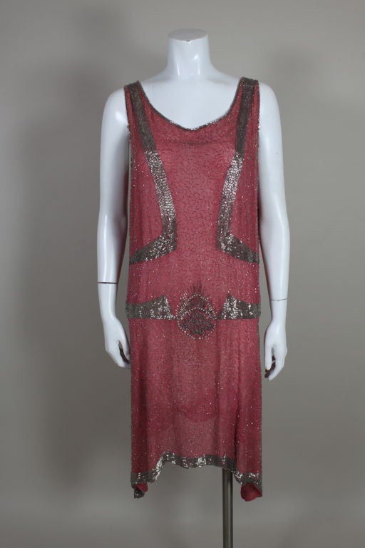 Absolutely stunning 1920s flapper dress made from a rosy pink cotton batiste embroidered with gunmetal glass beads. Bands of silver bugle beads are hand sewn along the hem and contours of the dress. A fabulous deco sunburst motif of rhinestones and