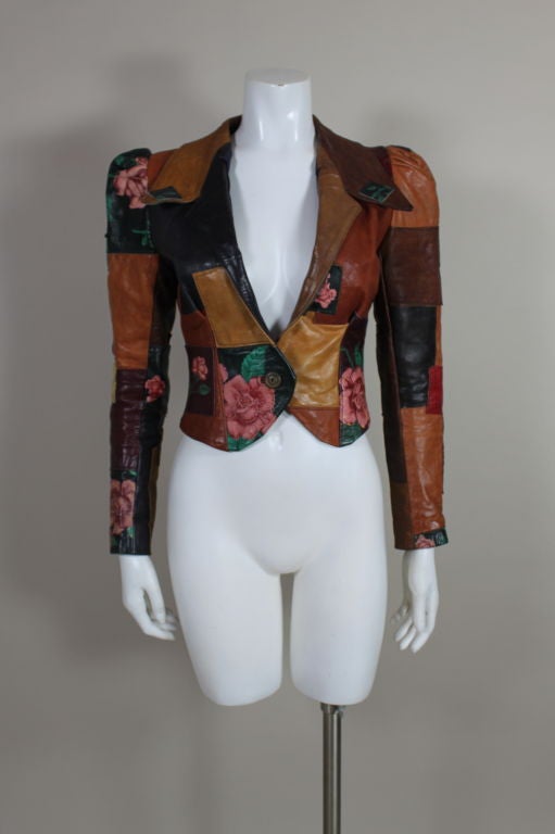 Amazingly sexy circa 1970’s jacket is snug and fitted with puff sleeves and a pointy notched collar. Patches of multi-colored leather, some printed with Sailor Jerry inspired roses, are stitched together to make for an earthy toned masterpiece. 