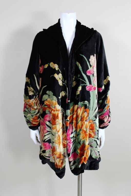 Luscious black silk velvet opera coat is printed with  a painterly floral in shades of fuschia, burnt orange and minty green. Sleeves are gathered and hand tacked into cascading ruffles. Lined in gold silk.<br />
<br />
Measurements-<br />
Bust: