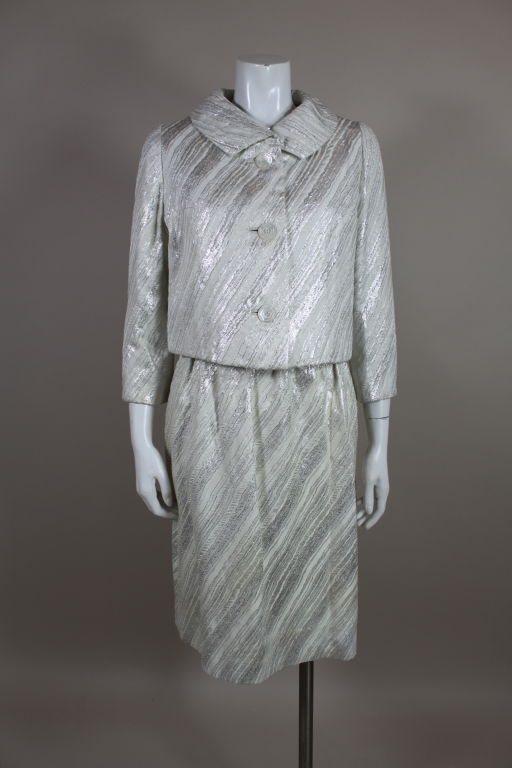 Gorgeous 1960s ensemble from American couturier, Mainbocher, includes a sleek dress and jacket done in the most beautiful silver lamé brocade. Brocade is woven into patterns of organic striations in shades of creamy white, subtle metallic gray and