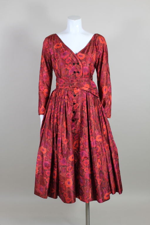 This 1950s unlabeled Galanos is made from the most gorgeous silk taffeta printed with a watercolor floral in shades of burgundy, magenta and pumpkin orange. Bodice has a lace-up back and a double-breasted button closure in front. Fit and flare