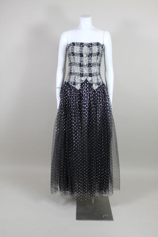 Fabulous ball gown from Bill Blass has a strapless black and white plaid tweed bodice flecked with metallic silver. Decorative rhinestone encrusted buttons are sewn along center front. Full, floor-sweeping skirt is made from metallic dot net tulle.