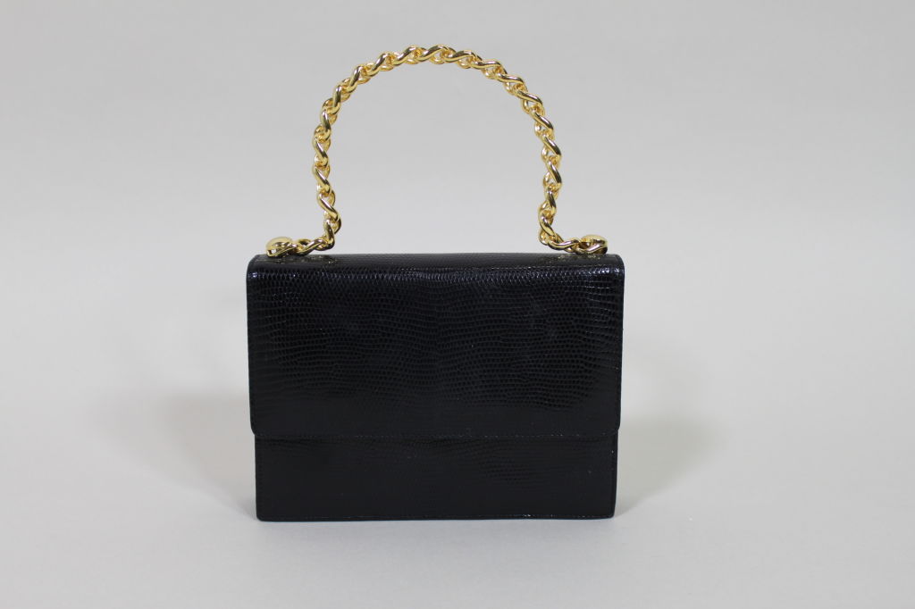 Chic structured handbag from Lana of London is made from supple, black reptile skin and has a molded gold chain handle. Purse has a fold over flap closure that snaps shut. 