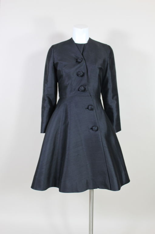 Gorgeous early 1960’s coat-dress from Anne Fogarty is done in an elegant raw silk. The silhouette has a fitted waist and flared skirt with textural knotted buttons fastening asymmetrically down the front. <br />
<br />
Measurements-<br />
<br