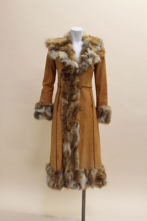 Bohemian luxe coat from iconic label North Beach Leather is made from buttery soft toffee colored leather. Seams are whip-stitched with suede cording. Coat is trimmed in tonal coyote fur and fastens with toggled buttons. Fully lined. Fits like a