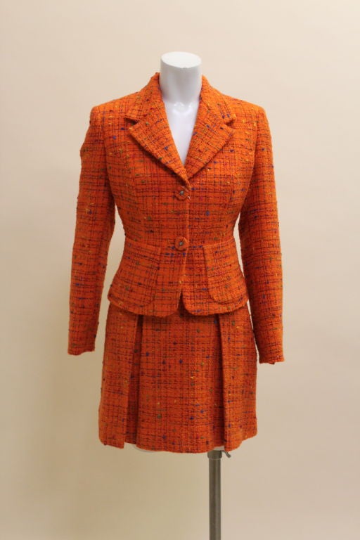 Brilliant orange two piece tweed suit from Versace Jeans Couture is flecked with vibrant multi colored slubs. Fitted jacket has front patch pockets and Versace medusa head logo buttons. Mini skirt has swingy kick pleats. Both pieces are fully lined.