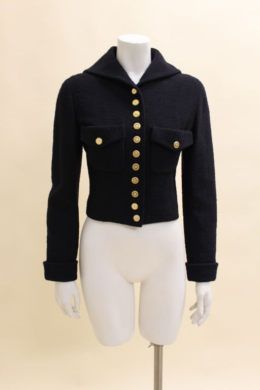 Fabulous Chanel jacket is done in a fitted silhouette with a sailor collar. A line of four-leaf clover emblazoned gold buttons fasten up the front and accent the fold-over patch pockets and cuffed sleeves. Fully lined. Lining is trimmed in iconic