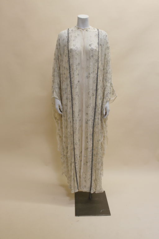 Absolutely magical Thea Porter Couture caftan is done in an ethereal white silk chiffon sprinkled with rings of metallic glitter. This gorgeous piece is edged in white silk satin cording. Sparkling silver braided trim accents seaming from front to