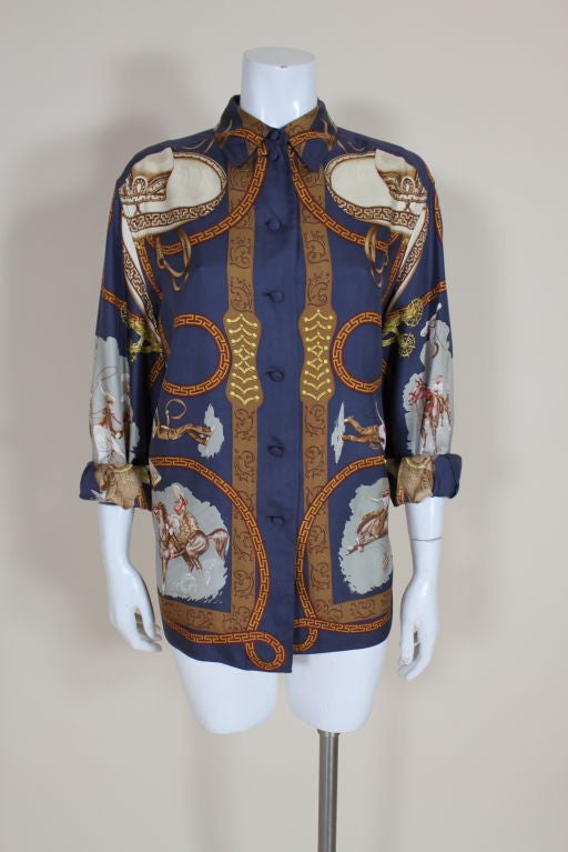 Classic button front silk blouse done in Hermés' iconic equestrian print features rodeo scenes with vaqueros and vaqueras framed by swirling lassos embellished with Greek keys, tooled leather holsters and golden pistols. <br />
<br