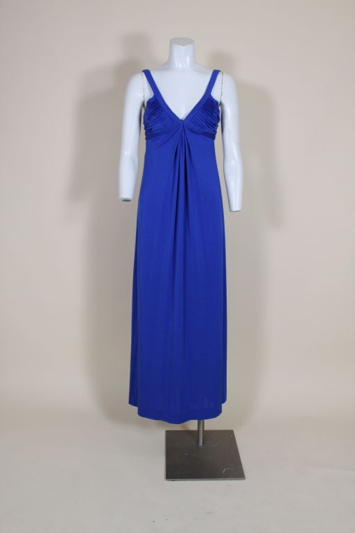 This stunning 1970's sapphire blue lycra jersey gown from Parisian designer Loris Azzaro features a sexy, deep-v neck bodice formed with hand sewn pleats. Empire silhouette gown has a long, slinky skirt that releases from pleated bodice. Fully