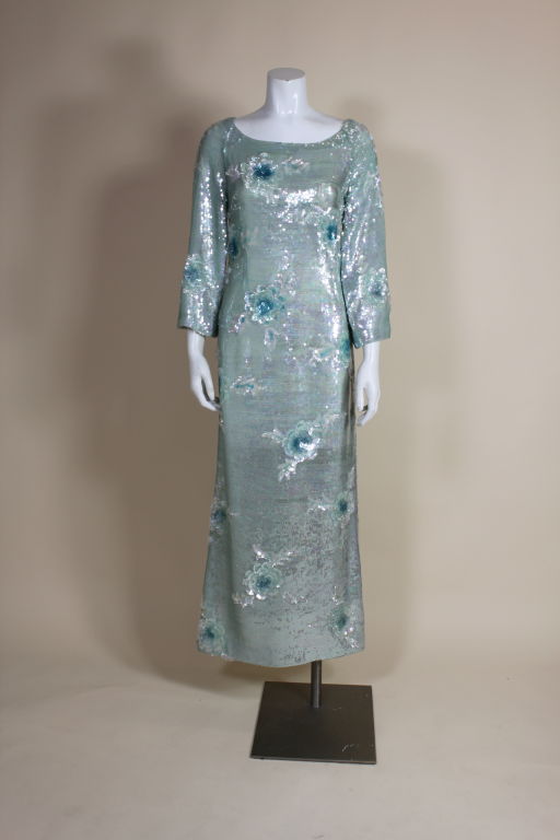 Gorgeous 1960's gown from couture designer Gaby of Spain is fully encrusted with ice blue iridescent sequins and spangling paillette flowers. Gown has a lovely scoop neck, slight bell sleeves and a subtle a-line silhouette. Fully lined in silk