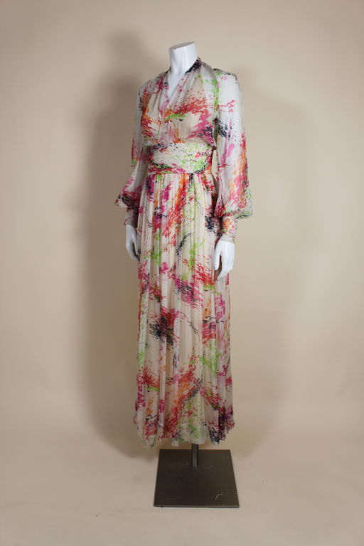 Absolutely beautiful circa 1970's gown from Christian Dior is made from diaphanous white silk chiffon printed with painterly splashes of radiant color. Chiffon top wraps and culminates in a high neck that buttons in the back. Sheer bodice is lined