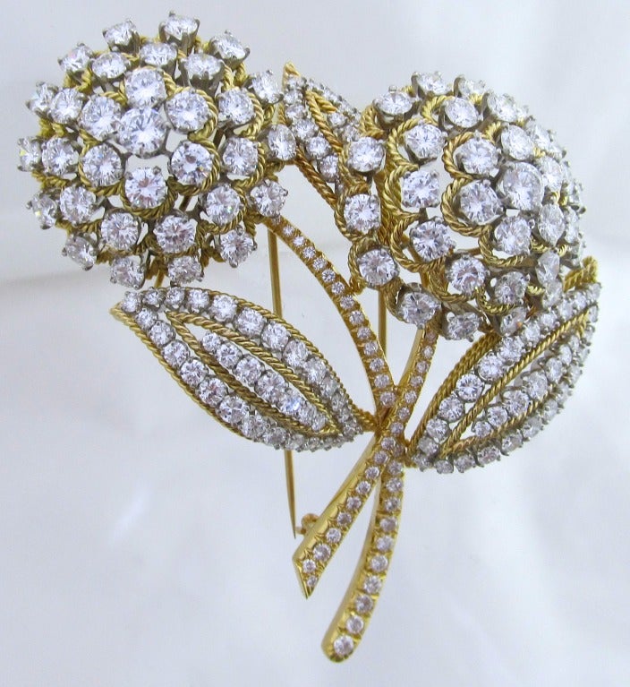 Van Cleef & Arpels   Brooch.
Designed as two diamond flowers, each with diamond dome cluster pistels, to the diamond leaves and stems, mounted in gold.
Estimated diamond weight is : 22 carats
Color: E/F
Clarity: VS1
Measurements:   2 7/8