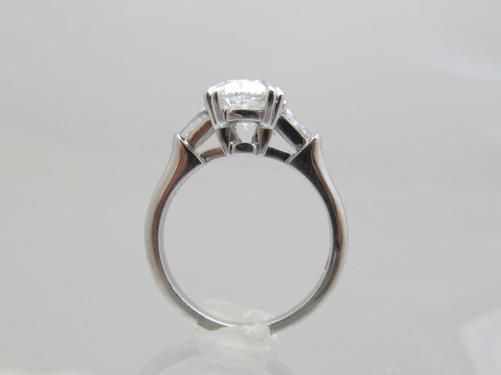 Harry Winston Solitaire Ring
Center diamond is :
Weight: 2.07 carats
Color:   F
Clarity: VS2
G.I.A. #    14433716
Set in platinum.
 Flanked by pair of tapered baguett diamonds with total weight of 0.35 carats.
Makers Hallmark:   HW