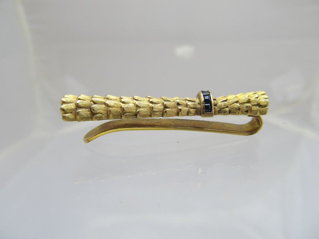 Cartier  18 k gold pin with channel style sapphire band.
Weiht is 6.9 DWT
Measurements:
length: 1.75 inches/ 4.5 cm
width : .5 inches/  1cm

Creator: Cartier