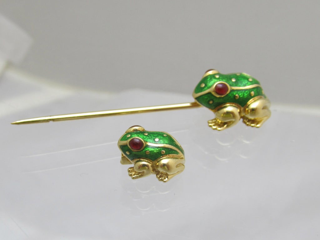 Adorable frog jabot by David Webb!
18kt gold with green enamel and cabochon ruby eyes.

In its original box.

Measurements:
Large Frog
-Length: .75 inches
Width: .5 inches
Little frog
-Length: .5 inches
Width: .5 inches
-Pin together