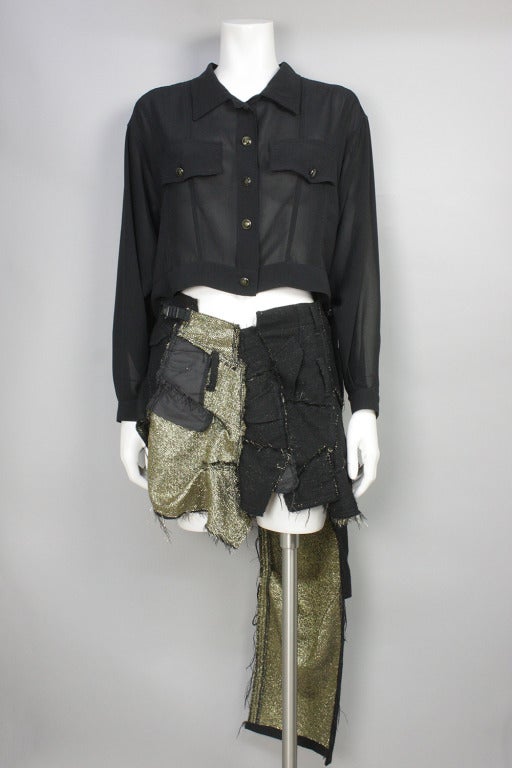 Black jean-style patchwork asymmetrical skirt with gold lame threading. Finished with raw edges and scattered buckles and belt loops. Wool blend fabric. Circa 1992.