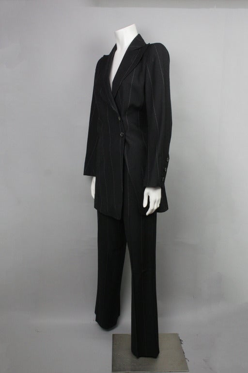 SALE! Originally $895
Black pinstripe wool suit. Asymmetrical jacket with inner tie closure for a defined waist. Straight legged pants with hook and eye at waistband. 

Please see last images for measurements.