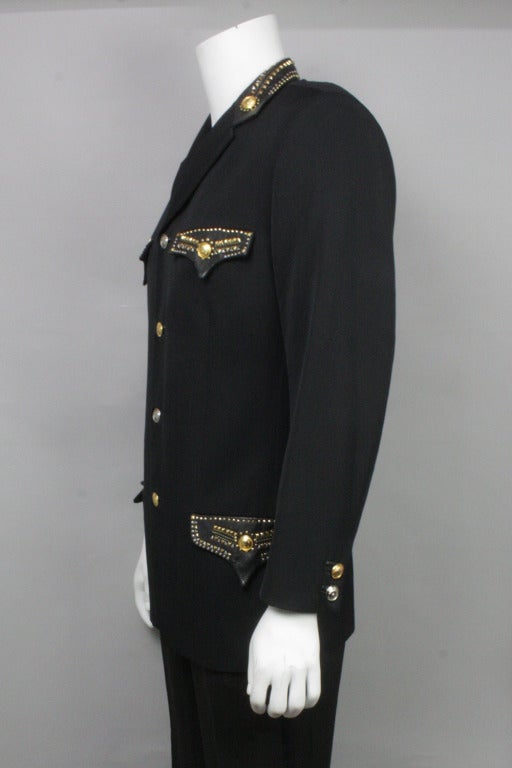 Black blazer adorned with gold and silver tone Medusa buttons. Western style pocket flaps and collar in leather with studs. Four outer pockets and two interior.
